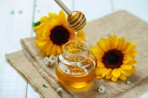 Honey jar with dipper and flowing honey, canvas background photo