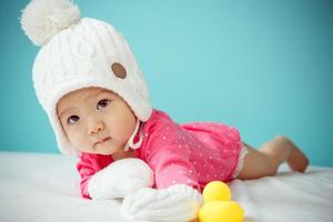 Baby wearing white knitted beanie in front of blue background photo