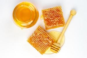 Honeycomb with jar and honey dipper isolated on white background photo
