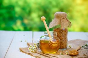 Glass bowls with honey another with pollen and propolis. Honey dipper, spoon, flower on the wooden photo