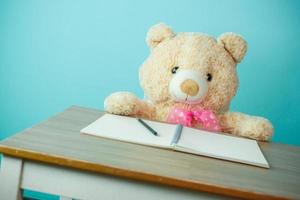 Conceptual shot of child education. Teddy bear writing on the table photo