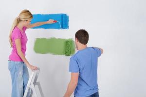 pareja feliz pintando una pared en su nuevo hogar foto