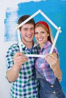 pareja feliz pintando una pared en su nuevo hogar foto