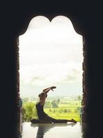 Silhouette young woman practicing yoga on the temple at sunset - vintage style color effect photo