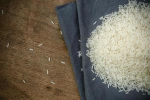 granos de arroz blanco con cuchara de madera sobre mesa de madera - enfoque suave foto
