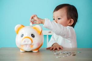 pequeña caja de dinero para bebés poniendo una moneda en una alcancía - niño ahorrando dinero para el concepto futuro foto