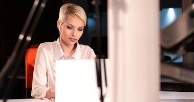 mujer que trabaja en la computadora portátil en la oficina nocturna foto