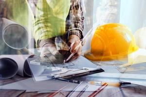 business hand working and laptop with on on architectural project at construction site at office desk in office photo