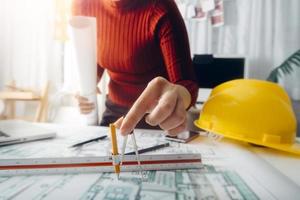 Two colleagues discussing data working and tablet, laptop with on on architectural project at construction site at desk in office photo