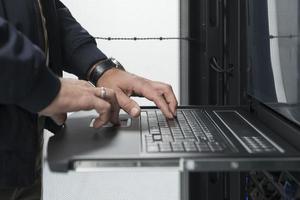 Close up on Data Center Engineer hands Using keyboard on a supercomputer Server Room Specialist Facility with Male System Administrator Working with Data Protection Network for Cyber Security. photo