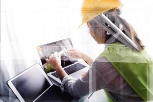 Two colleagues discussing data working and tablet, laptop with on on architectural project at construction site at desk in office photo