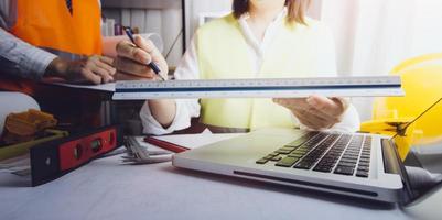 business hand working and laptop with on on architectural project at construction site at office desk in office photo