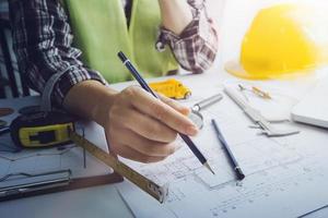 Two colleagues discussing data working and tablet, laptop with on on architectural project at construction site at desk in office photo