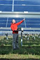 engineer using laptop at solar panels plant field photo