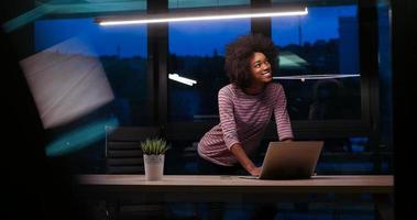 mujer de negocios negra que usa una computadora portátil en la oficina de inicio nocturno foto