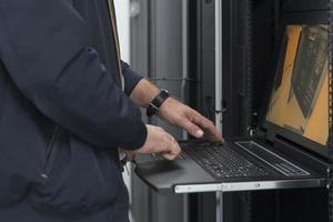 Close up on Data Center Engineer hands Using keyboard on a supercomputer Server Room Specialist Facility with Male System Administrator Working with Data Protection Network for Cyber Security. photo