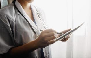Medicine doctor and stethoscope touching icon medical network connection with modern interface on digital tablet in hospital background. Medical technology network concept photo