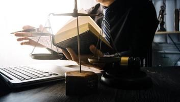 Business and lawyers discussing contract papers with brass scale on desk in office. Law, legal services, advice, justice and law concept picture with film grain effect photo