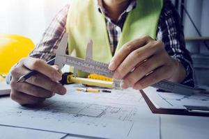Two colleagues discussing data working and tablet, laptop with on on architectural project at construction site at desk in office photo