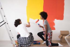 multiethnic couple painting interior wall photo