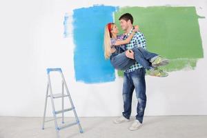 pareja feliz pintando una pared en su nuevo hogar foto