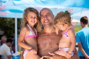 portrait of young happy father with daughters by the sea photo