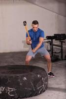 man workout with hammer and tractor tire photo