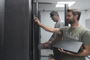 Technicians team updating hardware inspecting system performance in super computer server room or cryptocurrency mining farm. photo