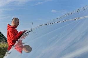 engineer using laptop at solar panels plant field photo