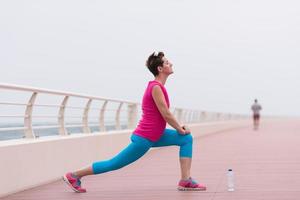 mujer estirándose y calentándose en el paseo marítimo foto