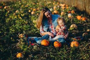 madre e hija en un campo con calabazas foto