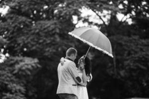 Young and beautiful European couple hiding from the rain under an umbrella photo