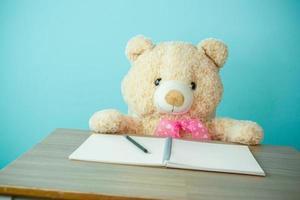 Conceptual shot of child education. Teddy bear writing on the table photo