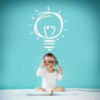 Little baby and blackboard with Light Bulbs on background, School concept photo