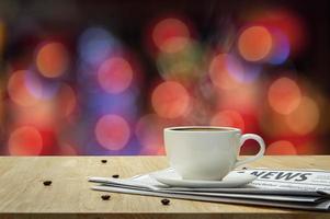 White cup of Espresso with Newspaper on the wooden table and the bokeh background photo