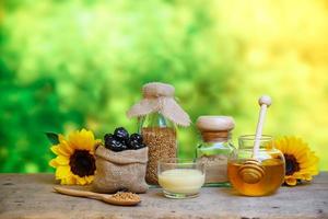 Glass bowls with honey another with pollen and propolis. Honey dipper, spoon, beeswax, sunflower on the wooden photo