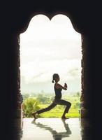 Silhouette young woman practicing yoga on the temple at sunset - vintage style color effect photo