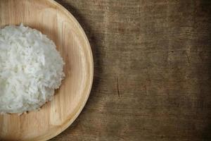 Organic White Rice in wooden dish on wooden table - soft focus photo