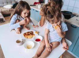 Mom and two daughters eat pancakes photo