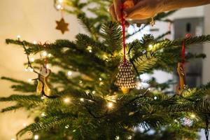 Female hand hangs a gingerbread snowflake on the Christmas tree photo