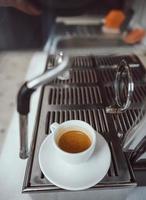 close-up view of glass cup with cappuccino and coffee machine photo