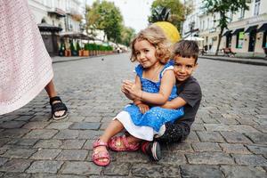 little boy and girl are sitting on the street photo