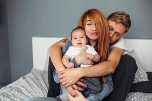 Happy family with newborn baby on the bed photo