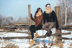 young couple sitting on old fence photo