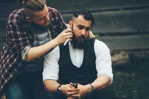 barber shaves a bearded man in vintage atmosphere photo