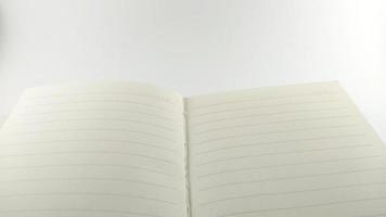 A creamy white notebook spread out in the center and placed on a white table. photo