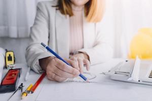 Dos colegas discutiendo el trabajo de datos y una tableta, un portátil con un proyecto arquitectónico en el sitio de construcción en un escritorio en la oficina foto