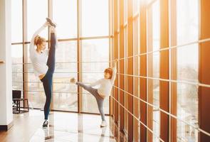 Mother learning daughter to make a high leg strech photo