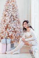 Young woman in an elegant dress near the Christmas tree photo
