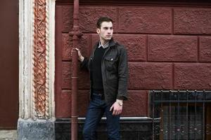 Male model in jeans on the background of a red wall photo